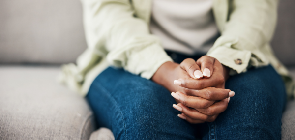 A woman sits on a sofa with her hands on her knees