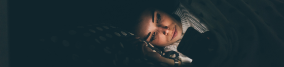 A woman using her phone in bed late at night
