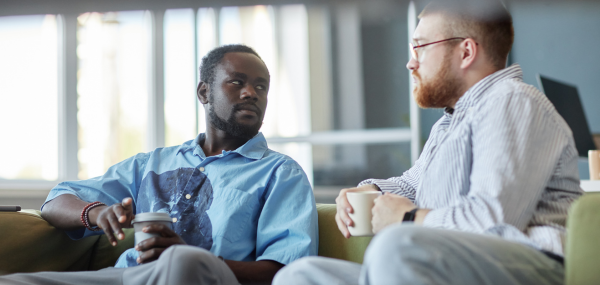 Two male colleagues have a chat over a coffee