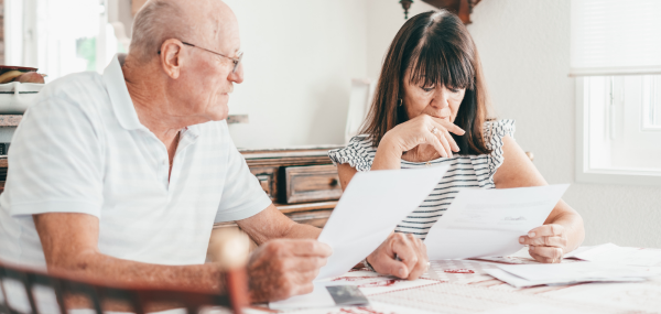 A middle-aged couple look over some documents at the kitchen table