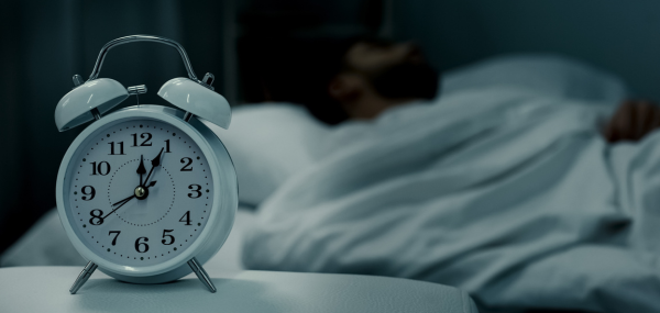 A bedside clock shows it's gone midnight